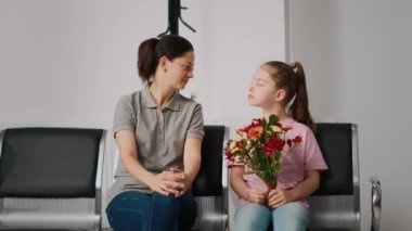 Anne ve küçük kız kontrol için bekleme alanında oturuyorlar, sağlık merkezindeki doktorla randevuları var. Kadın ve çocuk uzmanla görüşmek için bekliyorlar..