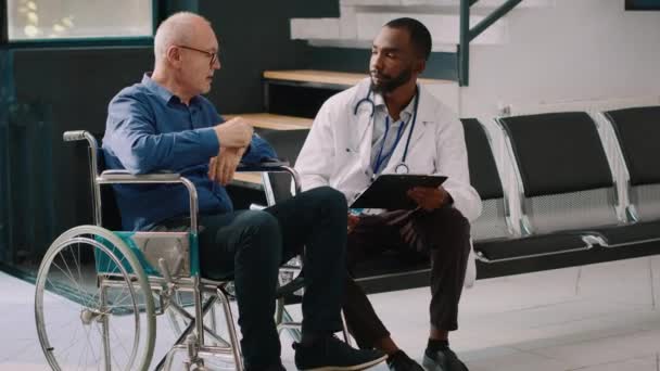 Afroameričtí Lékaři Konzultují Starým Mužem Vozíčku Vyplňují Lékařské Posudky Nemocniční — Stock video
