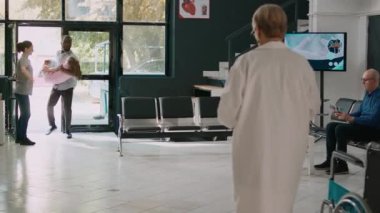 Baba, uzman, endişeli ebeveynlerden yardım almak için sağlık merkezinde bilinçsiz bir çocuk taşıyor. Doktorla acil durum görüşmesi yapmak için bekliyorlar. Lobideki hasta kıza tıbbi danışmanlık..