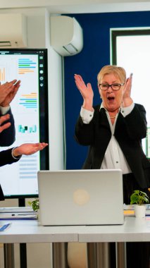 Genelevde toplanan yaratıcı iş ekibinin mutluluğu. İş ortakları başarılı bir anlaşmayı kutluyor ve kontrat imzalıyor. Olumlu duyguları olan etnik gruplar arası iş adamları..