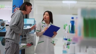 Eczacı, eczanede mide ağrısı için müşteriye yardım ediyor. Karın ağrısına karşı ilaç veriyor. Genç uzman, mide iltihabı olan hasta adama ilaç açıklıyor..