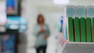 Asyalı müşteri kutuları sepete koyuyor, ecza ürünleri ya da raflardan takviyeler alıyor. Kadın ilaç ve vitamin paketlerine bakıyor, ilaç alıyor. El kamerasıyla..