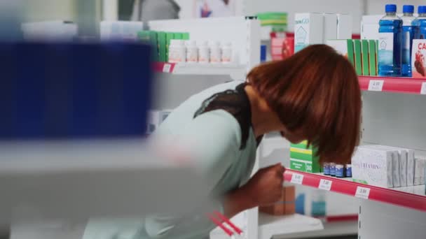 薬局の女性に薬の治療を説明する薬局のコンサルタントは 病気に対する薬のボトルを示しています 医療従事者はビタミンや薬について女性の顧客と話す — ストック動画
