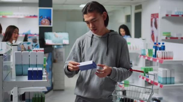 Asiatischer Mann Checkt Flaschen Und Schachteln Mit Pillen Der Apotheke — Stockvideo