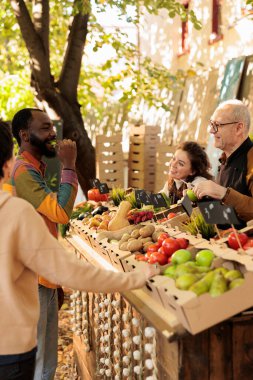 Genç mutlu Afrikalı adam yerel çiftçi pazarından doğal organik ürünler alırken elma tadıyor. Zenci müşteri taze yerel ürünler alırken yemek tadıyor.
