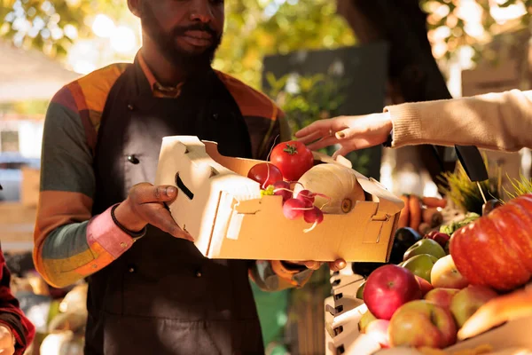 在农贸市场上 非洲裔美国男性农民向妇女赠送装满新鲜蔬菜的盒子 向女性客户出售健康的当地农产品的小企业主 — 图库照片