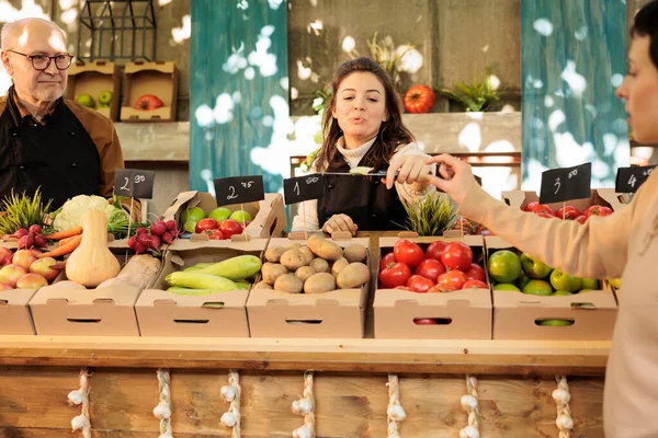 在当地农贸市场购买新鲜有机水果和蔬菜之前 快乐的女店员会向顾客提供切苹果 供他们试用 农场购物过程中品尝天然生物食品的微笑妇女 — 图库照片