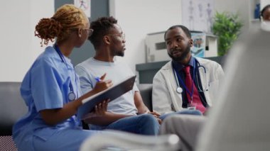 Klinik uzmanlarından oluşan bir ekip hastanenin resepsiyonunda genç bir adamla tıbbi danışmanlık yapıyor. Hekim ve hemşire hastalıkları ve sağlık sigortasını bireye açıklıyor. El kamerasıyla..