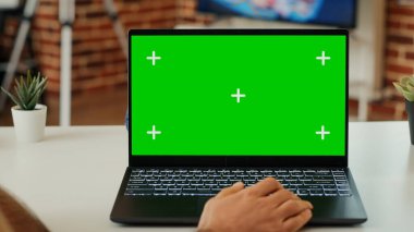 Genç yetişkin, kişisel bilgisayarda yeşil ekran görüntüsünü analiz ediyor, izole edilmiş model şablonuna bakıyor ve krom anahtarla çalışıyor. Evde dizüstü bilgisayarda boş telif alanı kullanmak. Kapat..