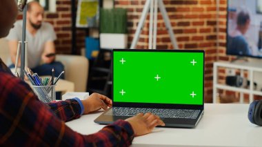 Bilgisayarda yeşil ekran görüntüsüne bakan ofis girişimcisi, kablosuz bilgisayarda boş model şablonu kullanıyor. Ana masadaki krom tuşlu kopya alanı arka planında çalışan kadın.