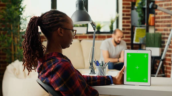 女性自由职业者在家里的写字台上观看显示绿色屏幕的数字平板电脑 使用带有绿色屏幕模拟模板的彩色键显示 分析设备上的隔离复制空间 — 图库照片