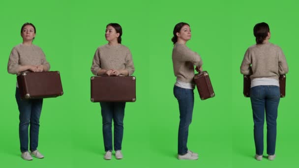 女性モデルは カメラでスーツケースの手荷物を保持し ブリーフケースや荷物で旅行に出発する準備 白人女性ありますヴィンテージ旅行バッグ立って上のフルボディグリーンバック — ストック動画