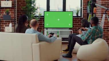 Yeşil ekran arka planında video oyunu oynayan mutlu arkadaşlar, izole edilmiş model şablonunda oyun yarışmasının tadını çıkarıyorlar. Boş krom anahtarda meydan okumayla eğleniyorum. Üçayak atışı.