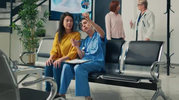 Ärztliche Assistentin Zeigt Älteren Asiatischen Frauen Wartebereich Eine Röntgenaufnahme Und — Stockvideo