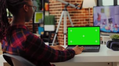 Laptop 'ta yeşil ekran şablonu kullanan Afro-Amerikan işçiler, izole görüntüyü krom anahtarla kontrol etmek için masada oturuyorlar. Taşınabilir pc üzerinde kopyalama alanı olan boş arkaplana bakıyorum.