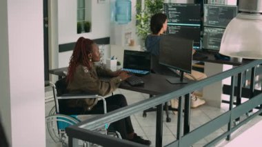 Tekerlekli sandalyedeki Afro-Amerikan uygulama geliştiricisi yazılım analizi programında, html senaryosunu web dilinde kodluyor. Yeni sunucu arayüzü kodlama bozukluğuna sahip sistem programcısı.