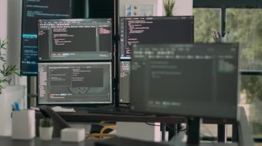 Sayısal programlama ağını ve yapay zeka ayrıştırma kodunu gösteren birden fazla ekranlı bir masa. Sunucuları ve veritabanı betiği olan boş yazılım geliştirme bürosu.