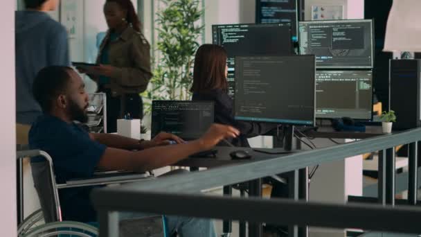 ソフトウェア開発者の車椅子ユーザーは Htmlスクリプトコードを操作し データベースとサーバーをチェックしてアプリシステムを開発します オフィスでプログラミングソースを使用して慢性障害を持つコーダー — ストック動画