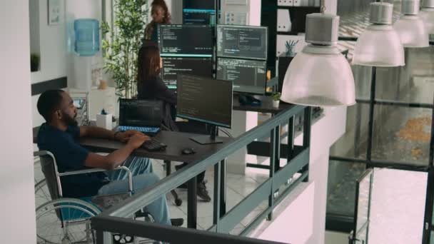 アフリカ系アメリカ人の開発者は コードを書くためにコンピュータを使用し ソフトウェア代理店でアルゴリズムを解析する 障害者フレンドリーなオフィスのデータベースとユーザーインターフェイスに取り組んでいるコーダー — ストック動画