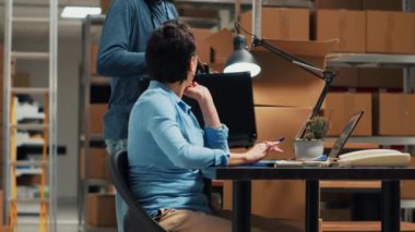 Kadın ve erkek, mal sevkiyatından önce stok ve envanter kontrolü yapıyor. Depoda iş planı üzerinde çalışıyor. Sahibi dizüstü bilgisayarda veri yazıyor, kalite kontrol yapıyor. El kamerasıyla..