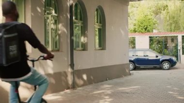 Teslimatçı, servis yapmak için müşterinin ön kapısına geliyor. Bisikletle restoran siparişini sırt çantasıyla getiriyor. Yemek servisi kuryesi bisikletle fast food paketi getiriyor..