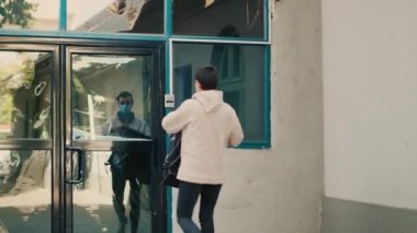 Kadın restoran kuryesi ön kapıdan fast food siparişi veriyor. Müşteri öğle yemeği için kese kağıdı alıyor. Paket teslimatı yapan bir servis elemanı. Covid 19 salgını sırasında, maske takıyordu..