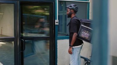 Gülümseyen kurye müşteriye fast food siparişiyle kağıt torba veriyor, ön kapıda ofis yemeği servisi var. Restorandan yemek getiren kadın, elinde yemek paketi olan müşteri..