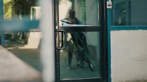 外卖工人骑自行车运送餐馆食品 在前门向妇女提供装有速递食品订单的纸袋 食物派递员携带装有饭盒的背包 — 图库视频影像