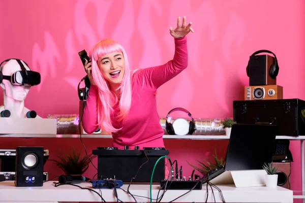 夜のクラブでプロのターンテーブルを使用して曲を演奏しながら ピンクの髪を持つアーティストは楽しんでいます 女性はDjテーブルダンスに立っている間ファンとアルバムを祝います — ストック写真