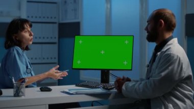 Hemşire ve doktor hasta uzmanlığını tartışıyor. Hastalık teşhisi raporlarını yeşil ekran ekranlı bilgisayarda inceliyorlar. Hastane ofisinde gece geç saatlere kadar çalışan sağlık personeli, sağlık hizmetleri...