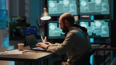 Bilgi yok etmek için sunucuyu hackleyen genç bir bilişim suçlusu dizüstü bilgisayar ve birden fazla ekranla kurumsal veri ağına giriyor. Veritabanını hacklemeye ve sistem verilerini çalmaya çalışıyorum, siber saldırı.
