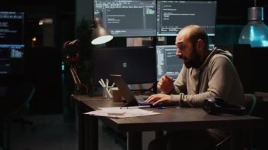 Genç adam yorgun hissediyor ve programlama kodu üzerinde çalışıyor, veritabanı bilgilerini ve dizüstü bilgisayarda html senaryosunu yazıyor. Yetişkin ofiste uyuyakalıyor, terminal penceresini kullanmaktan yoruluyor. El kamerasıyla..