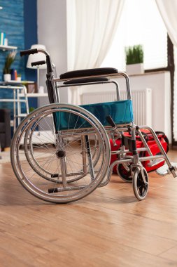 İçinde tıbbi tekerlekli sandalye olmayan boş bir oturma odası. Kırmızı fizik tedavi çantasının yanında özel fizik tedavi seansına hazır. Engelliler için destek merkezi.