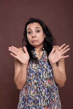 Hintli kadın avuçlarıyla hiç sorun çıkarmıyor, yavaşla, kameraya bakıyor. Kolları açık duran genç adam, tamam işaret, ön görüş stüdyo orta çekim kahverengi arka plan