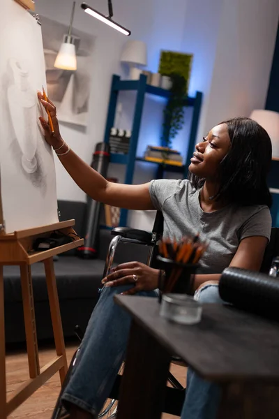 坐在轮椅上的女艺术学生在家里的艺术工作室里用空白画布画铅笔草图 具有艺术技巧的非裔美国人 在房子的阁楼上细画铅笔的框架 — 图库照片
