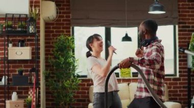 Çeşitli çiftler elektrikli süpürge ve paspasla oturma odasını temizlerken, şarkı söylerken ve müzik dinlerken eğleniyorlar. Genç mutlu partnerler bahar temizliğinin tadını çıkarıyor, yerleri süpürüyor..