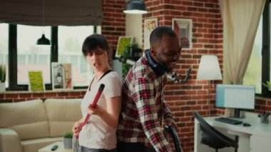 Neşeli insanlar, oturma odasında elektrikli süpürge kullanarak şarkı söyleyip, daireleri temizliyorlar. Genç, gülümseyen bir çift dans ediyor, müzik dinliyor, bahar temizliğiyle eğleniyor..