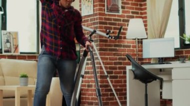 Afro-Amerikalı kadın kulaklıkla müzik dinliyor oturma odasında yerleri süpürüyor, elektrikli süpürge kullanıyor ve bahar temizliği yapıyor. Modern yetişkin dansı ve şarkı söyleme. El kamerasıyla..