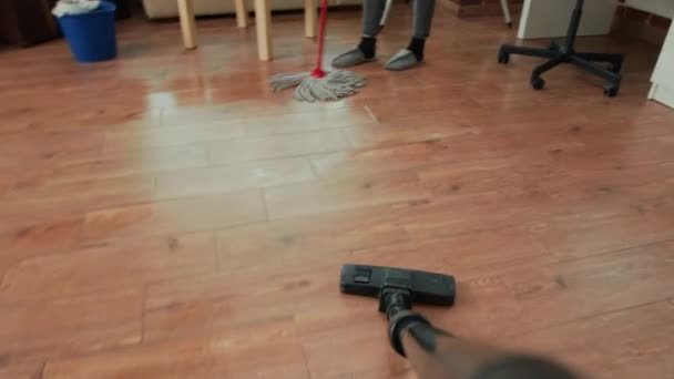 掃除機を使ってアパートを整理し 家庭で汚れやほこりを掃除する人のPov 若い大人は木製の床を掃除し ライフパートナーの清掃家具と雑用をしています 手持ち撮影 — ストック動画