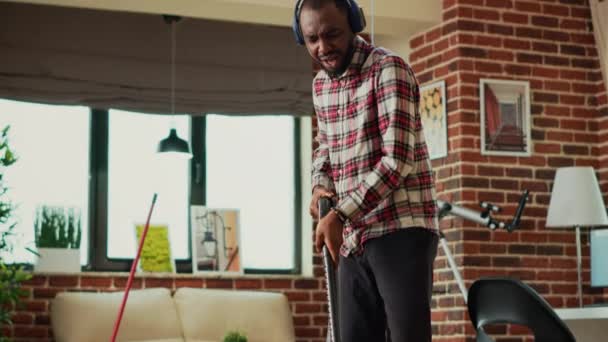 Afrykański Amerykanin Używający Odkurzacza Czyszczenia Drewnianych Podłóg Słuchania Muzyki Tańczenia — Wideo stockowe