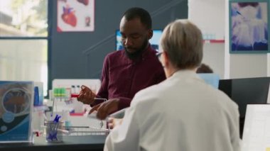 Afrika kökenli Amerikalı bir adam son sınıf öğrencisiyle eczacılık ürünleri hakkında konuşuyor. Eczanedeki ilaçlar ve haplar hakkında sorular soruyor. Eczanedeki eczacılara bakıyorum..