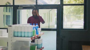 Acılı bir baş ağrısı ile eczaneye giren genç bir yetişkin kıdemli eczacıya tedaviyi veya ilaçları soruyor. Eczanedeki migren ve şakaklardan muzdarip müşteri.