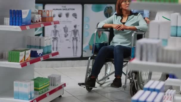 坐轮椅的客户接受专家的帮助 购买处方药和补品 与社会工作者一起到药房看病的残疾妇女 需要药物或药物 — 图库视频影像