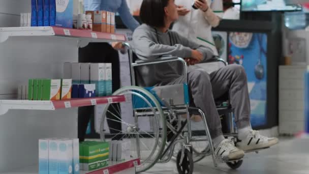 Мужчина Инвалид Колясочник Приходит Аптеку Таблетками Получая Помощь Азиатского Смотрителя — стоковое видео