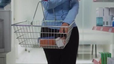 Eczane raflarından vitamin hapı seçen yaşlı bir müşteri ilaç paketlerini analiz ediyor. Reçeteli tedavi ya da ilaç almak isteyen Asyalı kadın, sağlık hizmetleri dükkanı.