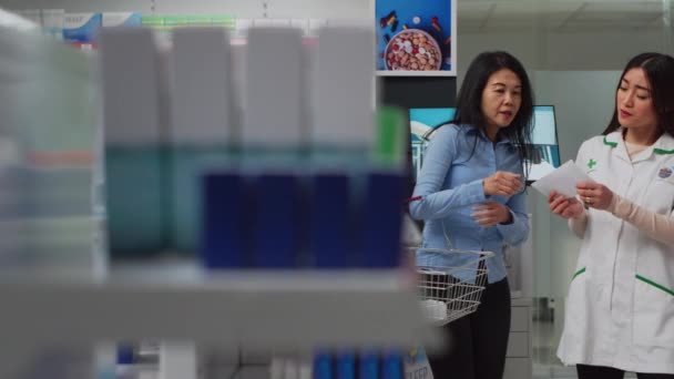 Asian Customer Showing Prescription Paper Employee Asking Help Finding Medicaments — Vídeo de stock