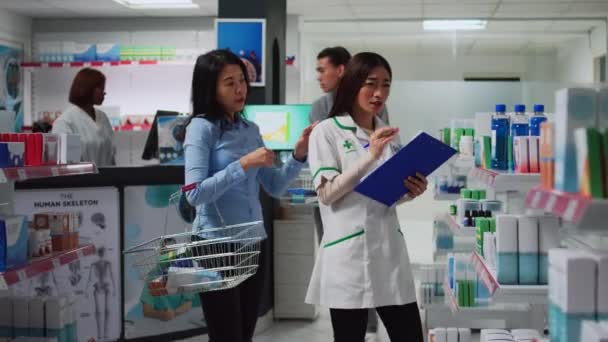 医療従事者は薬についてメモを取り 処方薬で顧客を助けます ドラッグストアで紙を使用して医療製品や薬を分析する薬剤師 — ストック動画