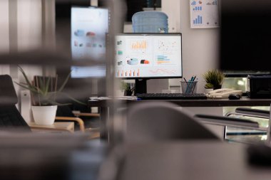 Statistical analysis company with financial growth charts on desktop computer screen in the afternoon. Empty office with no staff working in it with graphs on electronic devices.