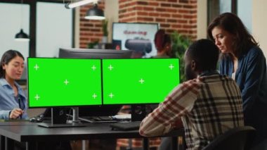 Diverse colleagues looking at blank greenscreen template on computers, working with isolated chroma key display in office. Man and woman using mockup copyspace background on modern pc.