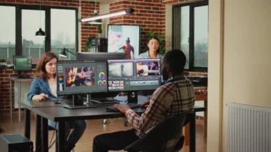 Creative filmmakers doing teamwork to edit video footage, using videography software in agency studio. Diverse colleagues working on film montage editing as graphic designers or artists.